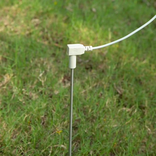Photo of a grounding rod being inserted into the soil, connected by a 12-meter cable running to an indoor earthing mat, illustrating the setup process for establishing an effective grounding system.